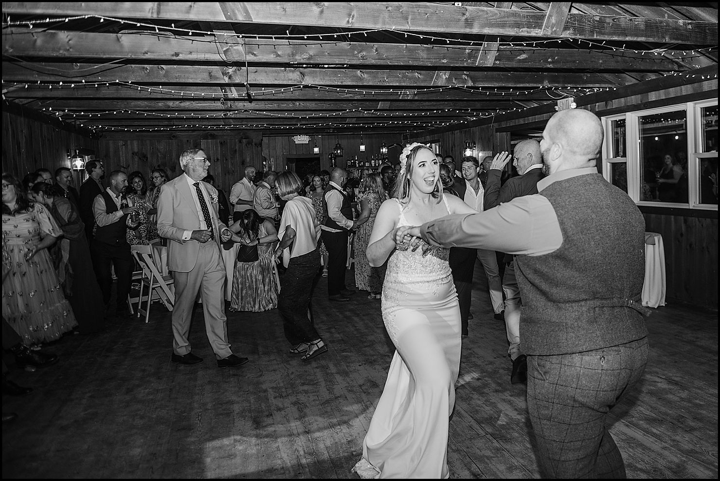 A bride and groom dance during a reception in a boathouse.