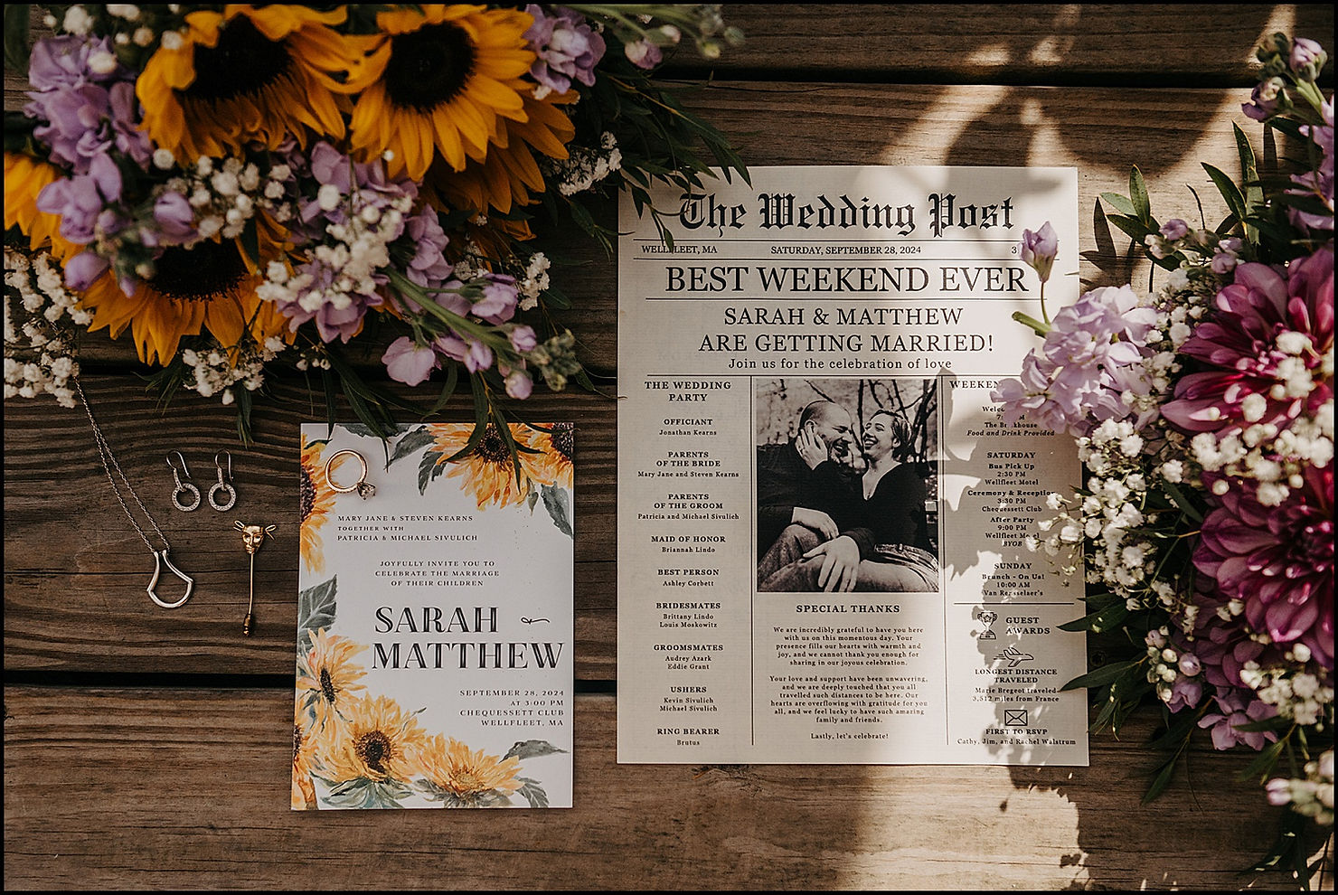 A wedding invitation suite sits on a wooden table beside a sunflower bridal bouquet.