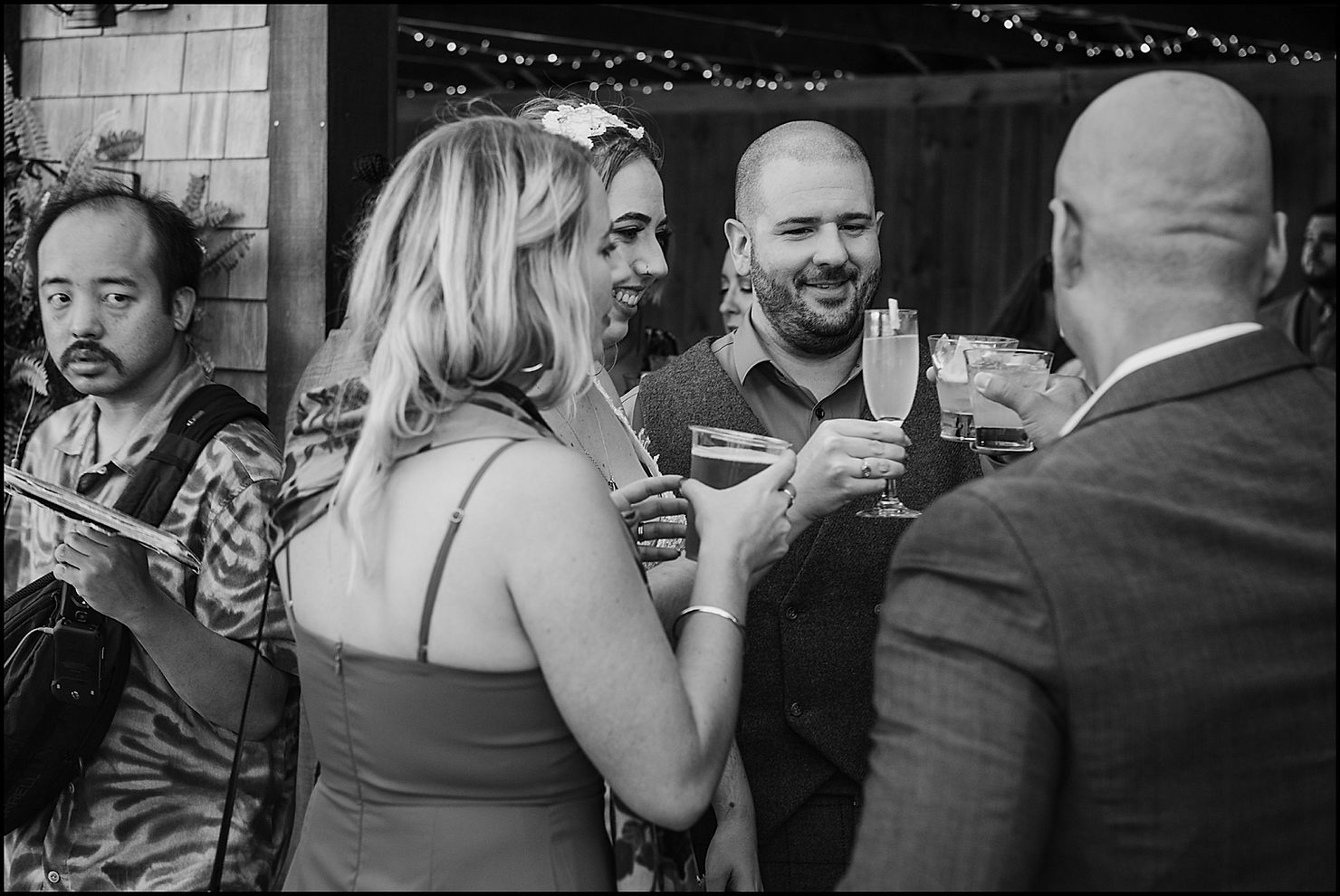 A bride and groom clink glasses with wedding guests during cocktail hour.