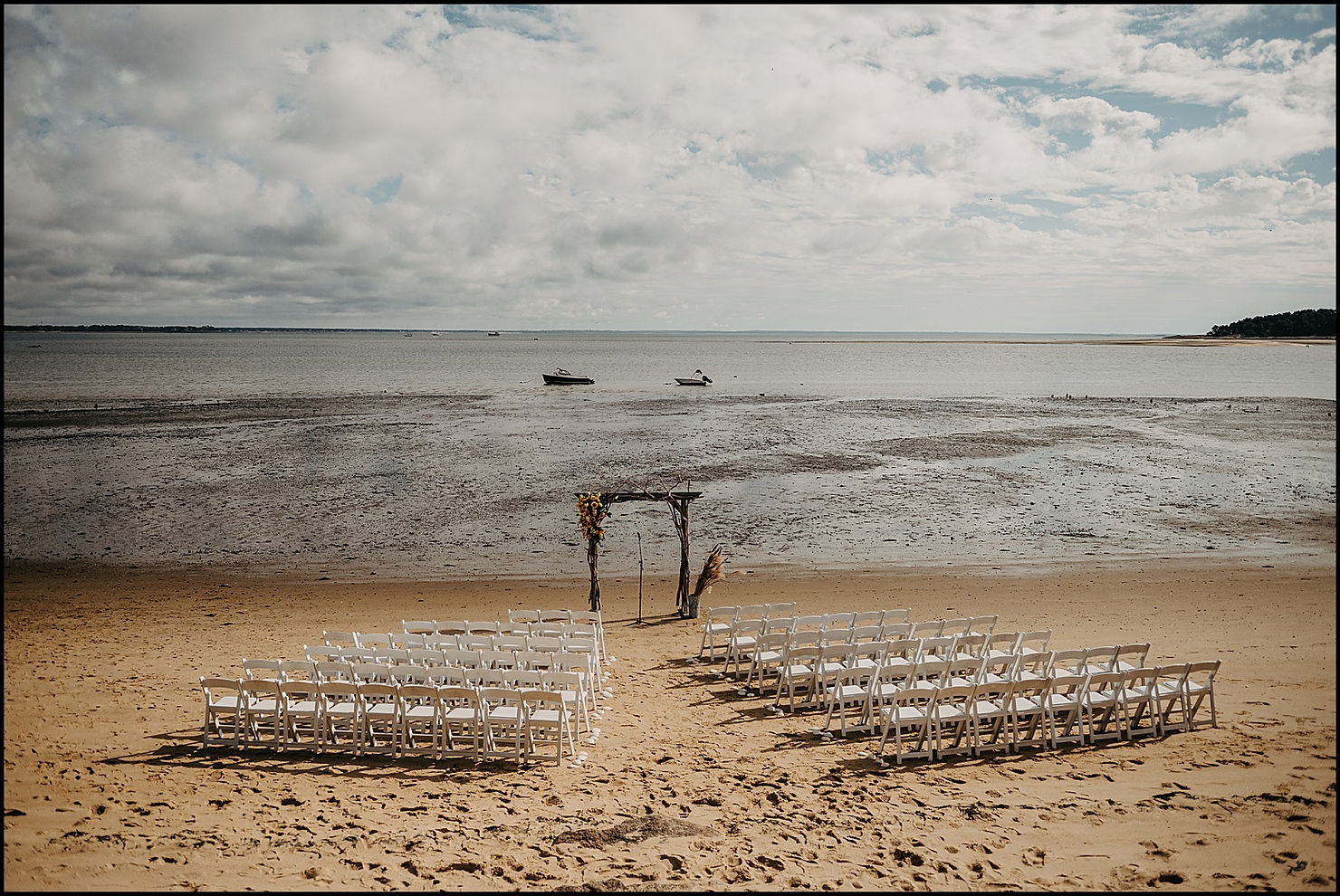 Chairs and a wedding arch sit ready for a beach wedding at a Cape Code wedding venue.