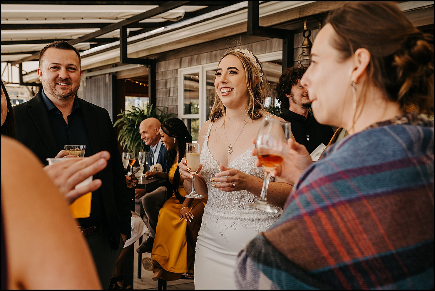A bride laughs as she listens to a wedding guest tell a story during cocktail hour at a Chequessett Club wedding.