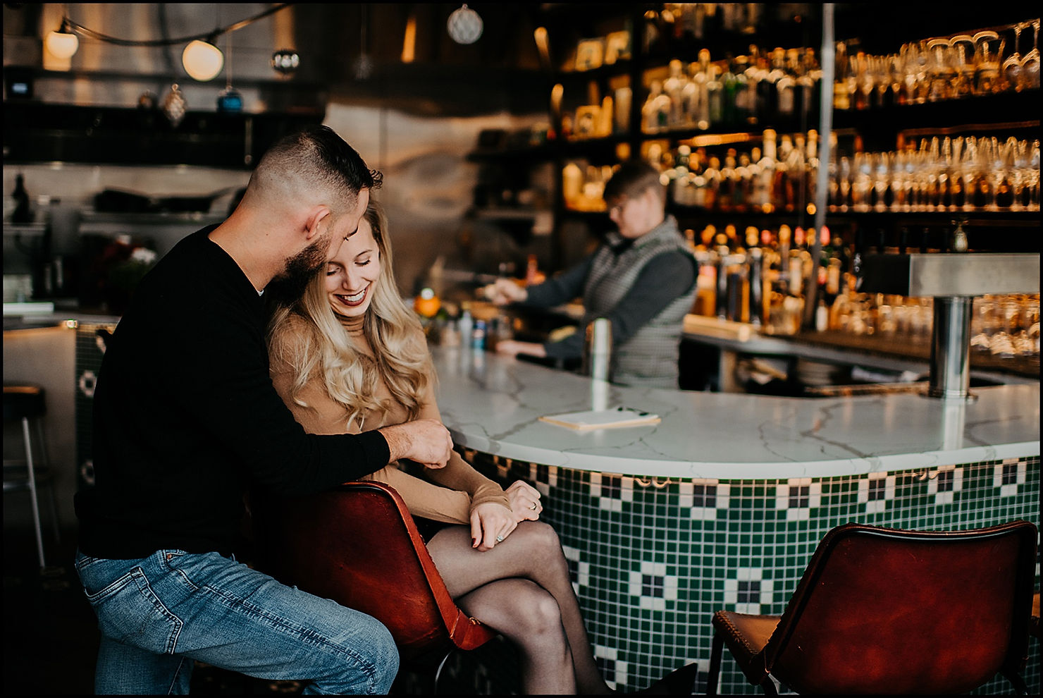 A woman leans on a man beside a tiled bar inside The Little Club Buffalo.
