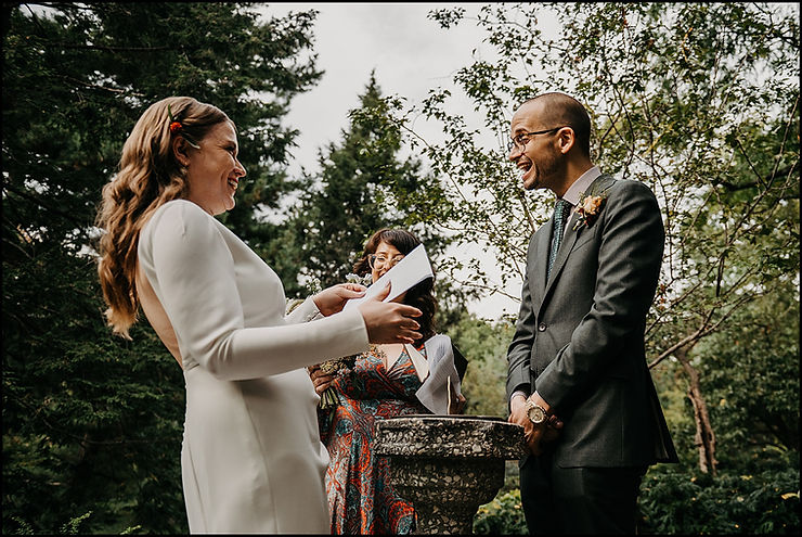 A bride and groom laugh as they exchange vows at a garden ceremony at a New York City wedding venue.