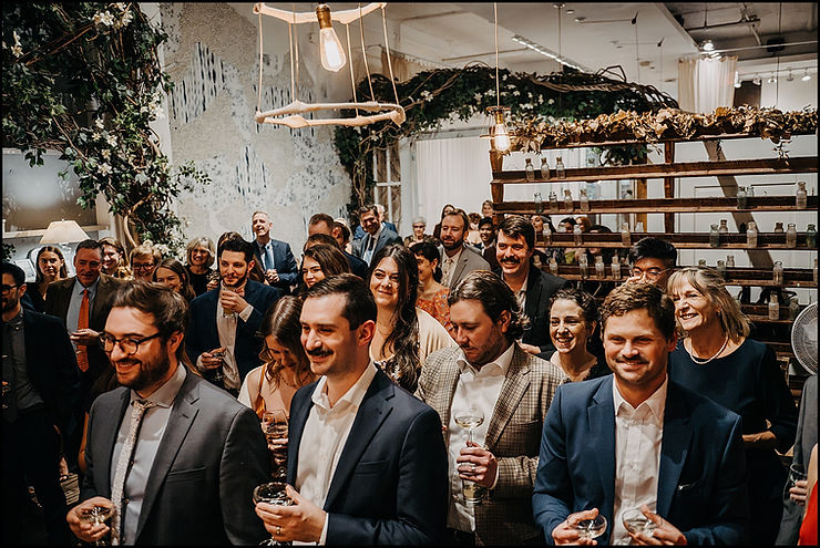 Wedding guests hold champagne and listen to a toast in the dining room at Maman Tribeca.