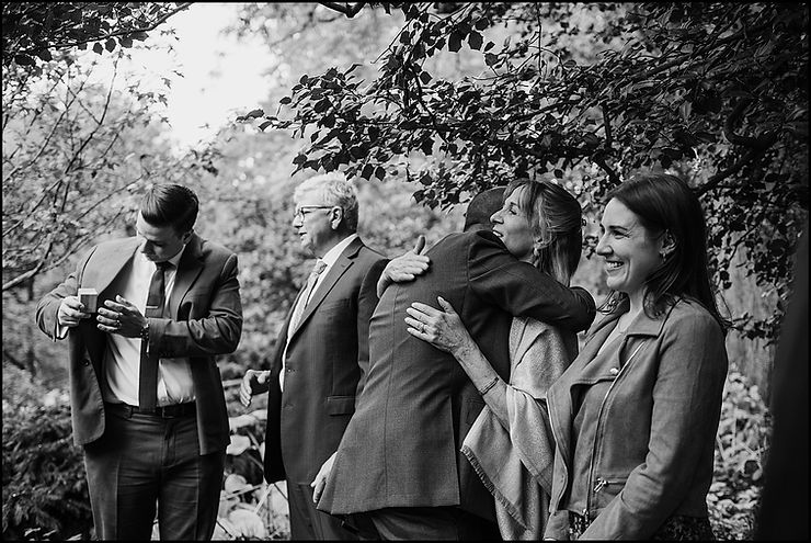 A groom hugs his mom after an outdoor wedding ceremony.