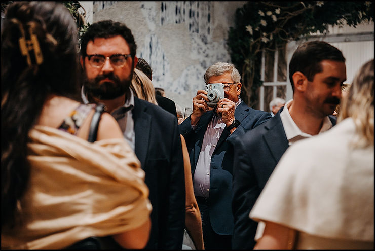 A wedding guest takes a photo with an instant film camera during cocktail hour.
